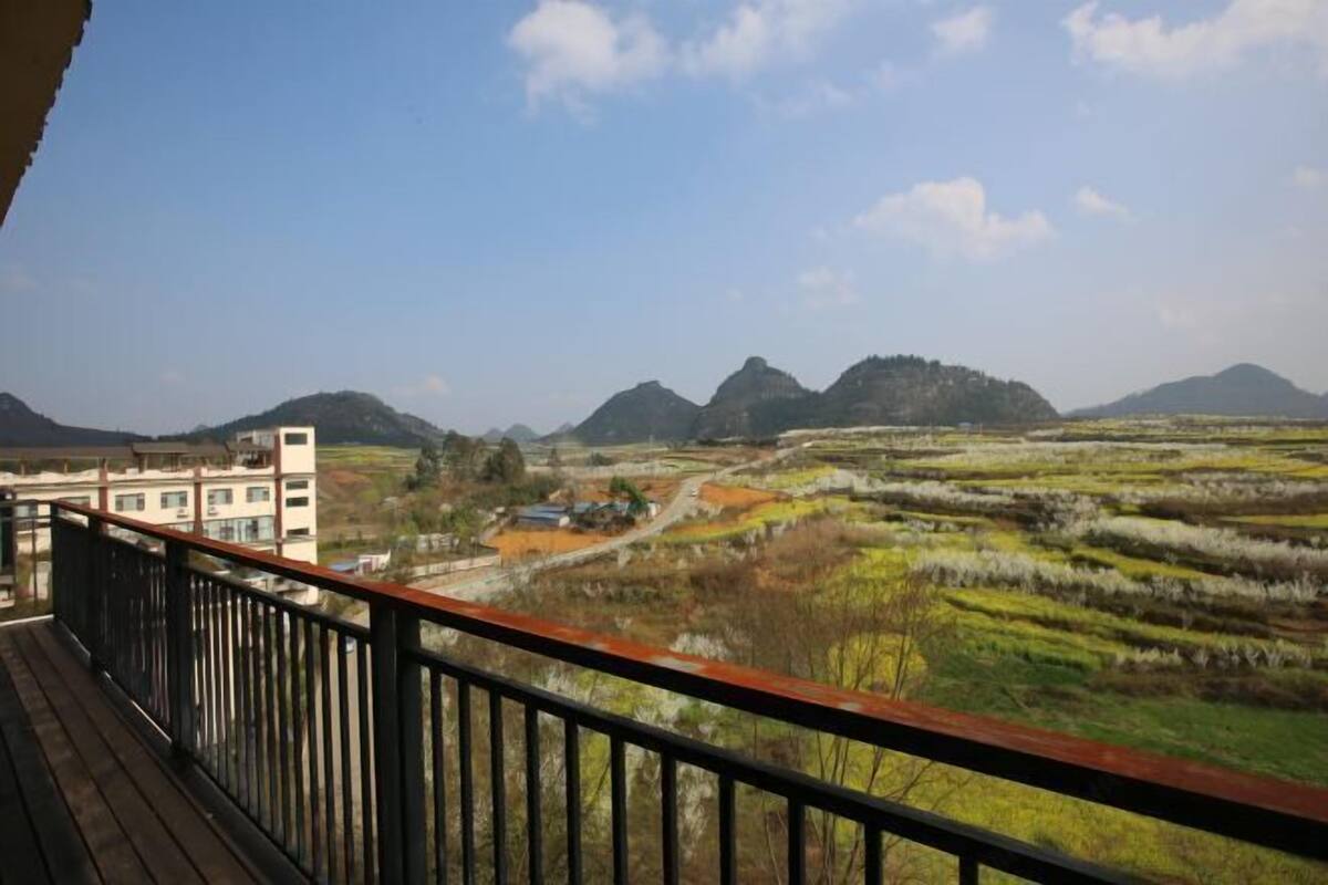 A balcony with a view of a mountainous landscape and a building in the foreground.