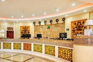 Un área de recepción con mostrador curvo, múltiples monitores y paneles decorativos en la pared.