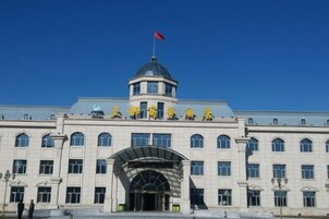 Un edificio grande con una cúpula central, múltiples ventanas y una bandera en la parte superior.