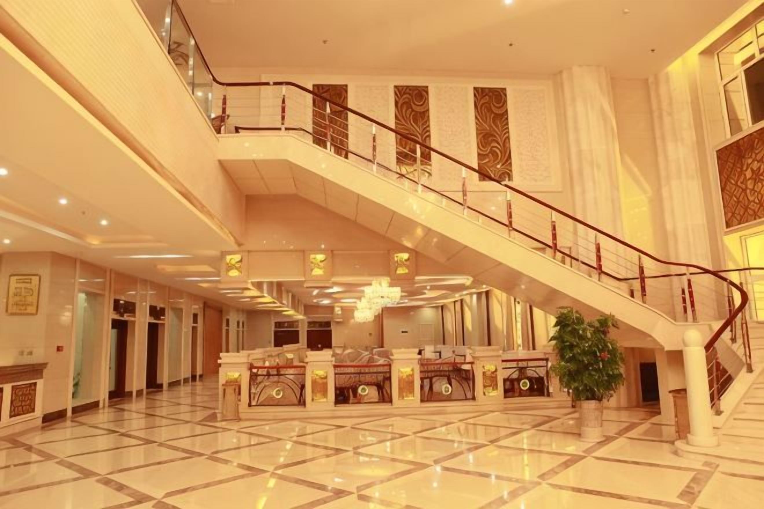 A spacious lobby with a central staircase, polished floors, and a reception area.
