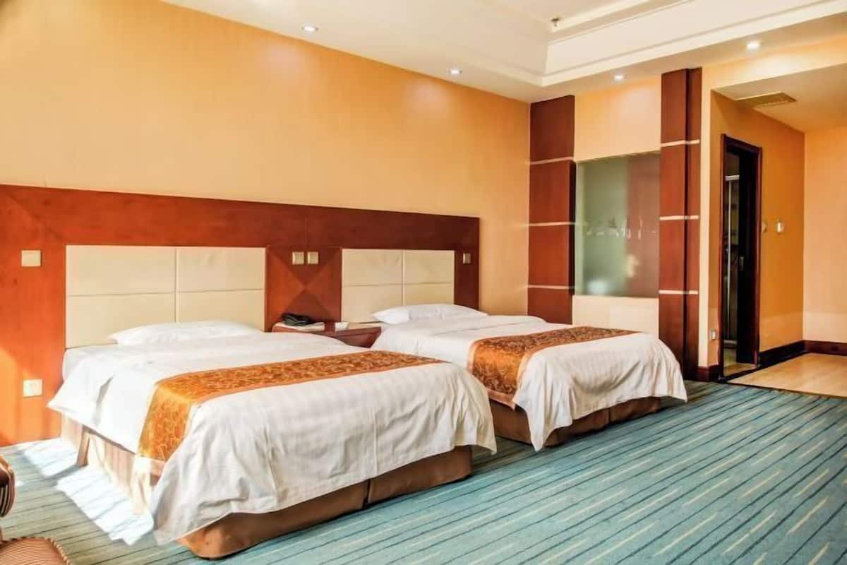 A hotel room with two beds, a wooden headboard, and a large mirror.