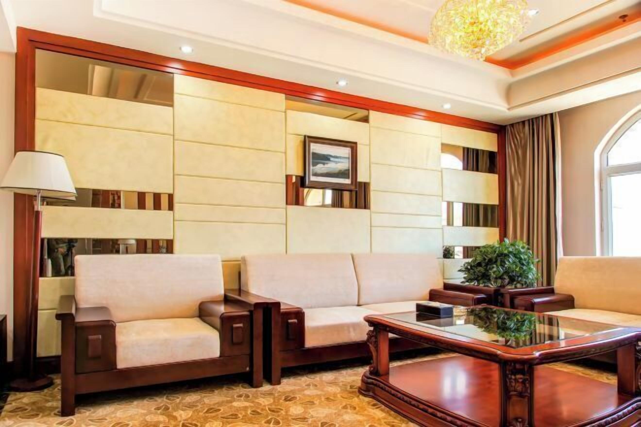 A room with a sofa, a coffee table, a lamp, and a large mirror.