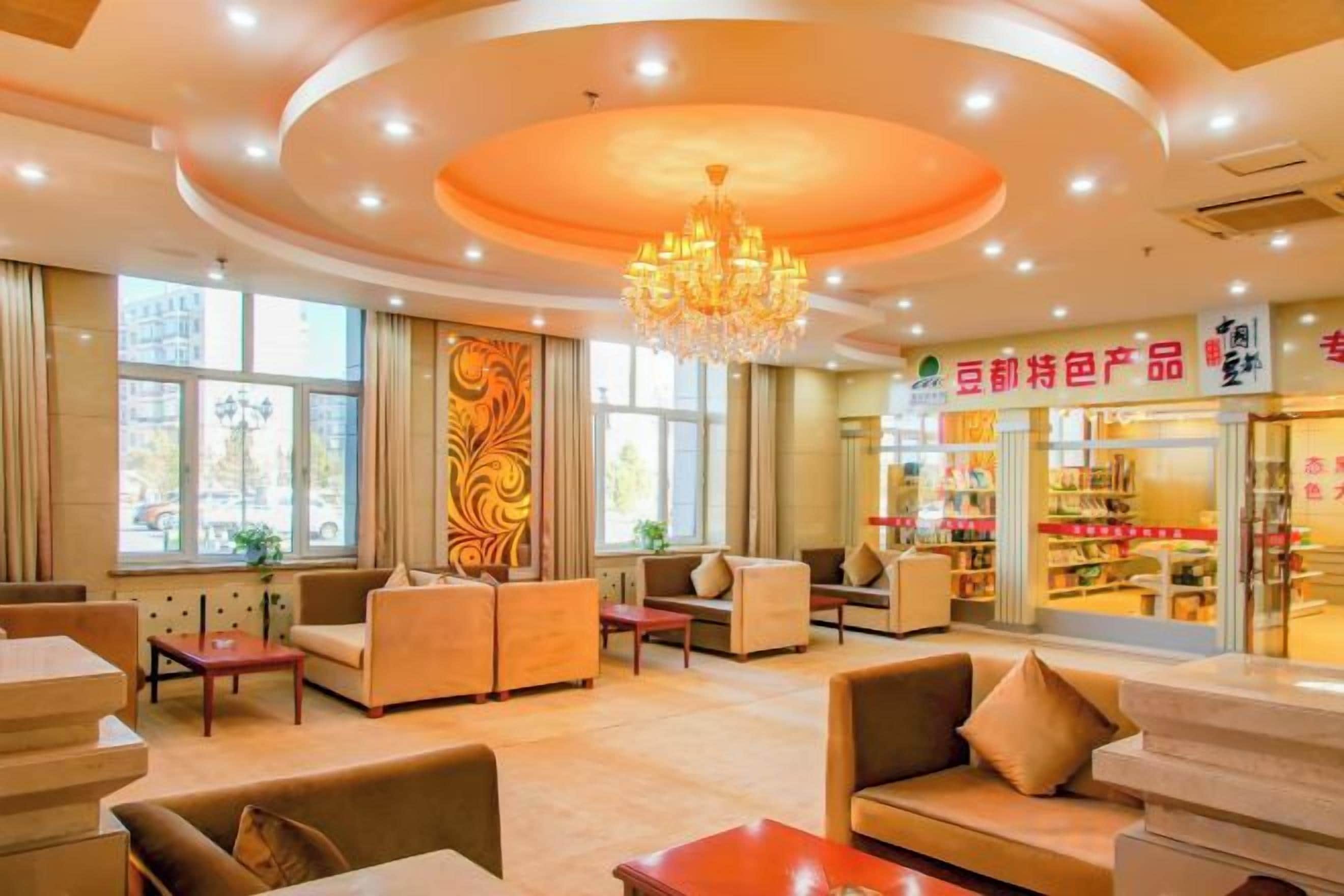 Eine Hotelhalle mit Sitzbereichen, einem Kronleuchter und einem sichtbaren Geschäft mit Beschilderung.