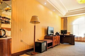 A hotel room with a wooden wall, a flat-screen TV, a desk, a lamp, and a window with curtains. - Doudu Business Hotel (Nenjiang)