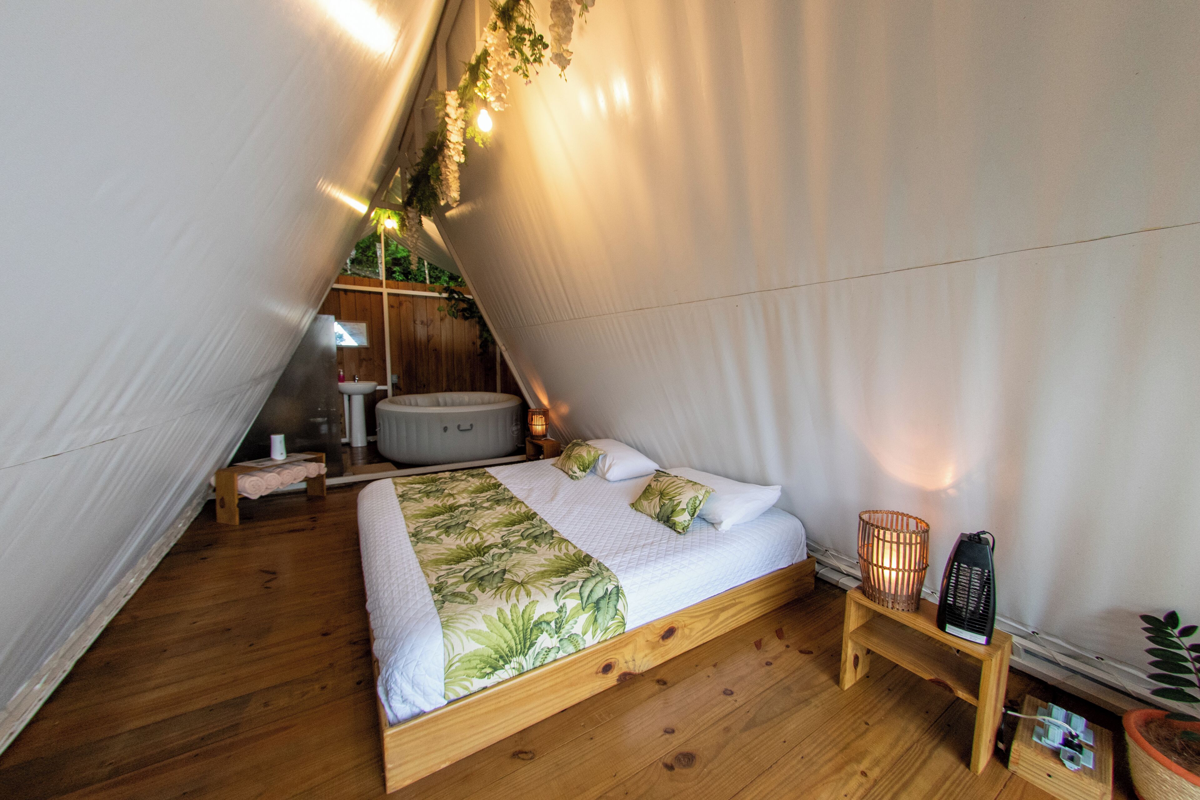 A cozy, triangular bedroom with a wooden bed, a small bedside table, a nightstand, and a potted plant.