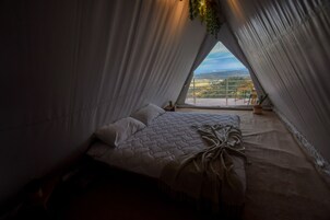 A cozy, triangular bedroom with a large window offering a scenic view.