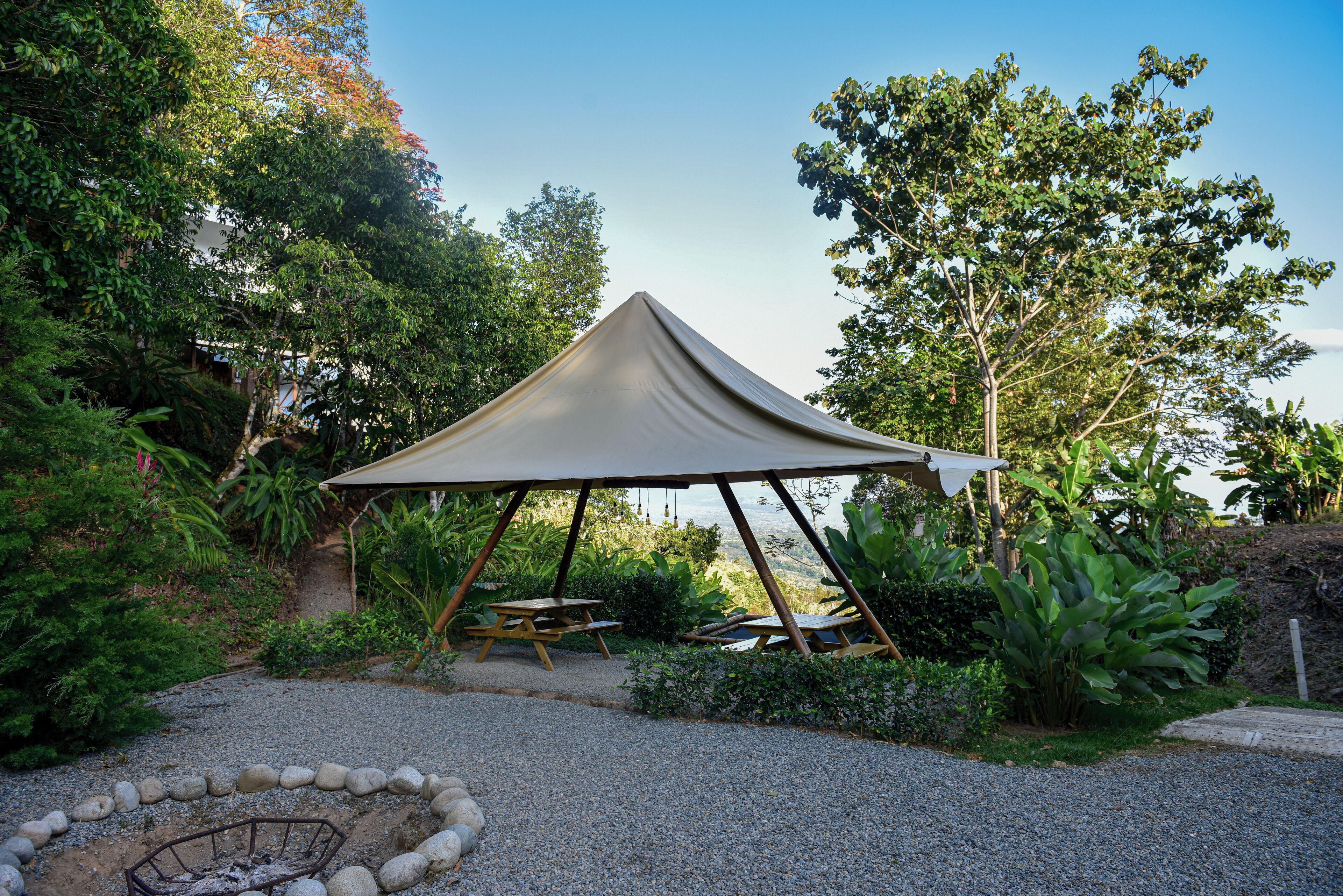 A tented outdoor area with a picnic table and a fire pit.
