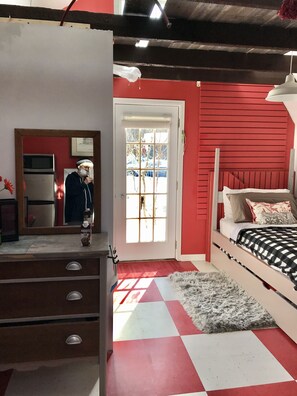 Cozy retreat with a bed, wooden headboard, and a window offering a view of the surrounding landscape.
