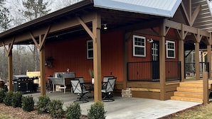 Un chalet rustique doté d’un patio couvert, d’un espace salon extérieur et d’un coin barbecue.