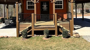 Une cabane rustique avec une façade en bois, une véranda dotée d’une balustrade et une porte sur laquelle est apposée une enseigne.