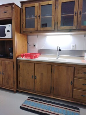 Compact kitchen with glass-fronted cabinets, stainless steel sink, and modern faucet.