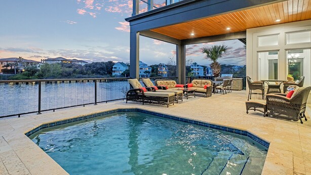 A pool area with lounge chairs and a view of the water. - Only Good Vibes|Golf Cart to Beach|Lakefront Home w/ Stunning Views & Pool (Destin)