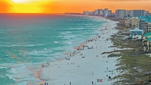 A beach with a sunset, a boardwalk, and buildings along the shore. - Only Good Vibes|Golf Cart to Beach|Lakefront Home w/ Stunning Views & Pool (Destin)