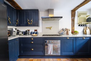 A modern kitchen with dark blue cabinets, stainless steel appliances, and a tiled backsplash.