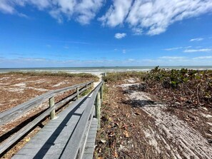 A wooden boardwalk leading to a beach with a clear sky. - The Beach House at Windrush (Cocoa Beach)