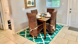 A dining area with a table set for four, surrounded by wicker chairs.