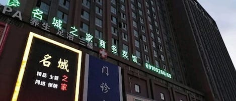 A multi-story building with illuminated signage indicating various businesses, including a commercial space and a residential area.