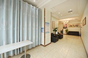 A hotel lobby with a reception desk, seating area, and a large window.