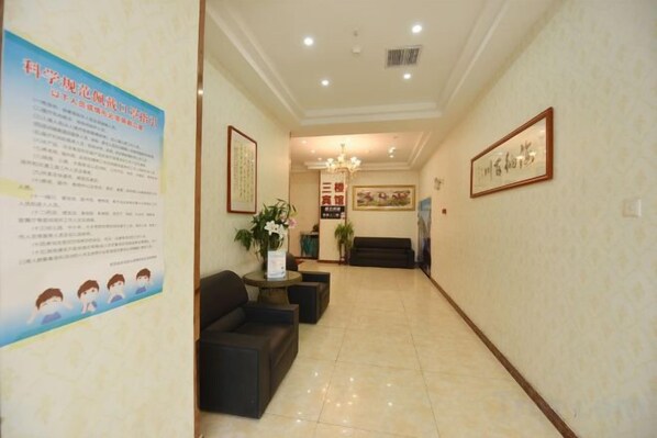 A hotel lobby with a reception desk, seating area, and a poster on the wall. - Mingcheng Home Business Hotel (Hefei)