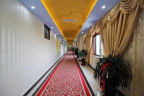 A long hallway with a red carpet, potted plants, and a golden curtain on the right. - Mingcheng Home Business Hotel (Hefei)