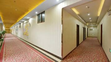 Un pasillo de hotel con alfombra roja, puertas a ambos lados y techo amarillo.