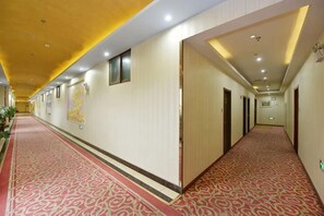 Un pasillo de hotel con alfombra roja, puertas a ambos lados y techo amarillo.