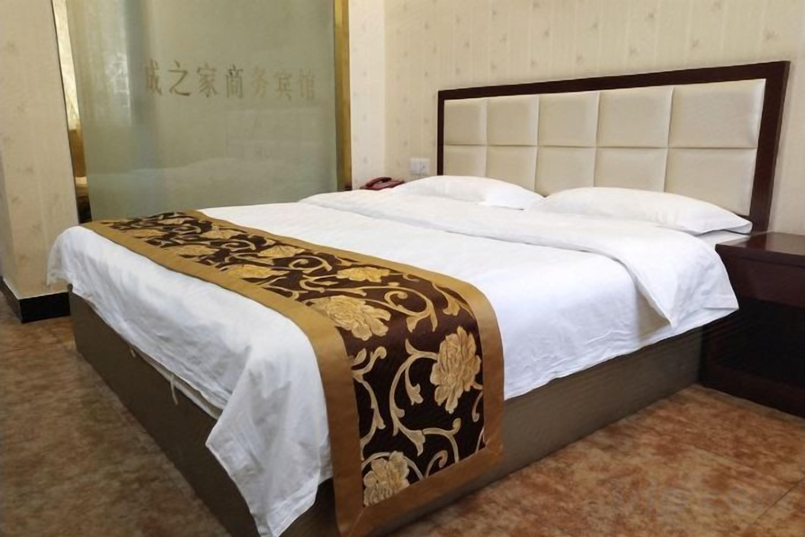 A hotel room with a bed, a bedside table, and a wall with a decorative panel.