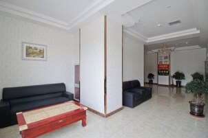 A room with a sofa, a tatami mat, a pillar, a reception desk, and a potted plant.