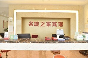 Un comptoir dâaccueil avec un panneau indicateur, des chaises, un ordinateur et quelques fournitures de bureau.