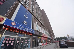 A commercial building with multiple storefronts, including a large blue sign with Chinese characters. - Mingcheng Home Business Hotel (Hefei)