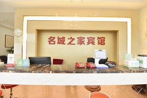 Balcão de recepção com computador, telefone e placa com caracteres chineses.