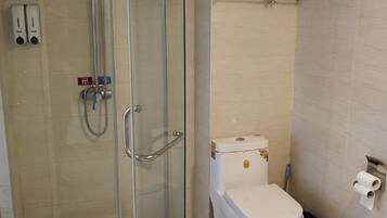 A bathroom with a glass-enclosed shower, a toilet, and a towel rack.
