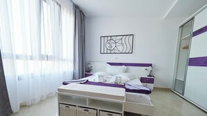 A modern bedroom with a bed, bedside tables, a wardrobe, and a large window with curtains. - Small Villa Emy Exclusive (Sporades)