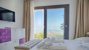 Une chambre d’hôtel avec un lit, un banc, une télévision et un balcon avec des rideaux.
