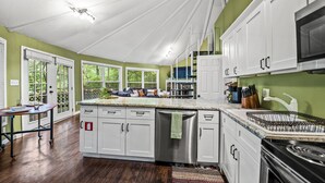 Une cuisine avec des meubles blancs, un lave-vaisselle en acier inoxydable et une cuisinière noire.