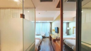 A hotel room with two beds, a desk, a chair, a TV, and a window with curtains. - Jiaxing Hotel (Ordos)