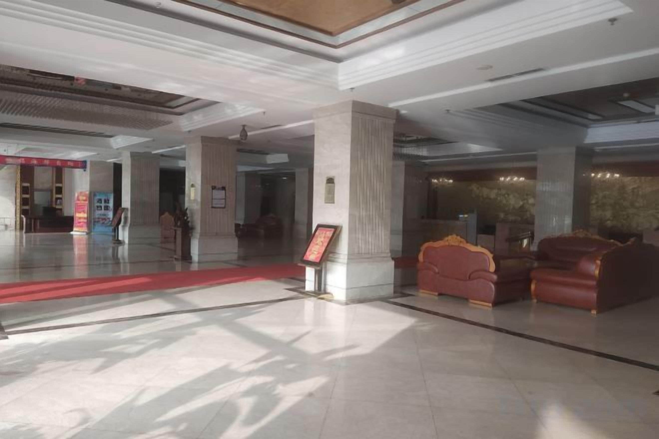 A spacious lobby with a red carpet, a reception desk, and leather seating.