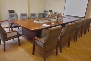 A conference room with a large rectangular table, multiple chairs, and a projector screen.