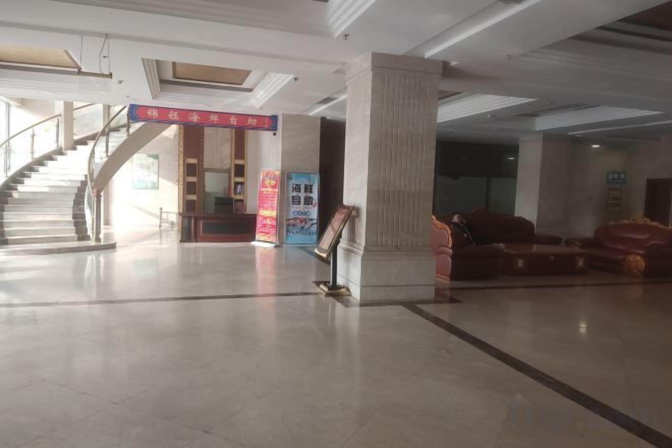 A lobby with a staircase, a reception desk, and a red banner.