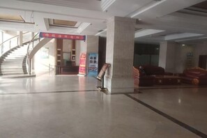 A lobby with a staircase, a reception desk, and a red banner. - Jiaxing Hotel (Ordos)