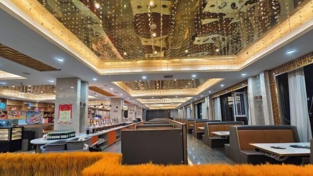 A modern restaurant interior with high ceilings, decorative lighting, and plush seating areas. - Jiaxing Hotel (Ordos)