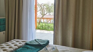 Une chambre d’hôtel avec un lit, une vue sur l’extérieur et une pergola en bois.