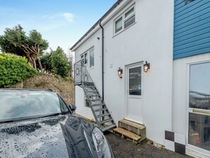 Un bâtiment blanc avec une porte bleue, un escalier et deux lampes fixées au mur.