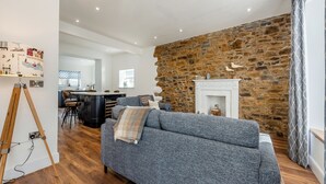 Una sala de estar moderna con una pared de piedra, una chimenea y un sofá gris.