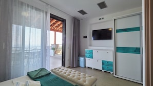 A hotel room with a bed, a bench, a TV, a wardrobe, and a balcony with outdoor seating. - Villa Noa Exclusive 4 Bedrooms (Skiathos)