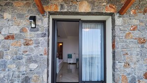 A stone facade with a sliding glass door leading to a room with a bed and a bathroom. - Villa Noa Exclusive 4 Bedrooms (Skiathos)
