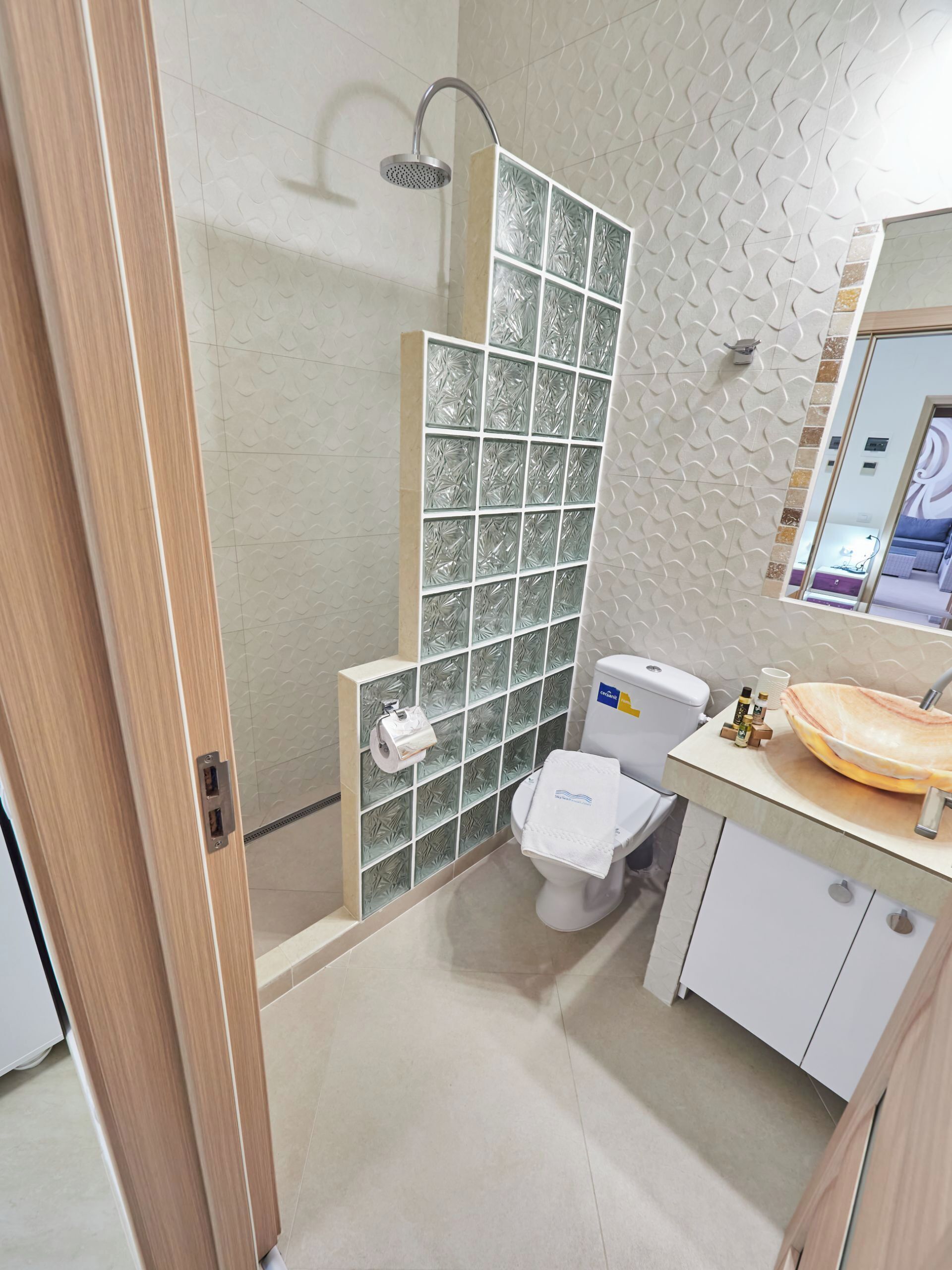Un baño moderno con cabina de ducha de vidrio, inodoro y tocador con lavamanos.