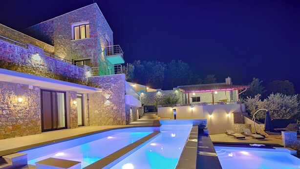 A modern villa with a swimming pool, stone exterior, and outdoor seating area. - Villa Linda (Skiathos)