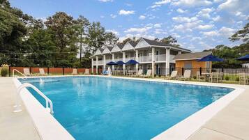 A swimming pool with a white deck and lounge chairs.