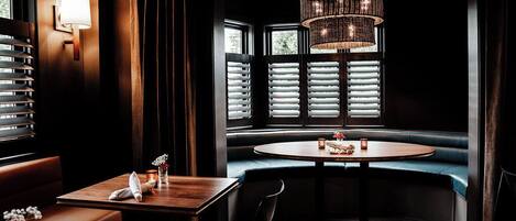 A restaurant with a round table, a bench, and a chandelier.